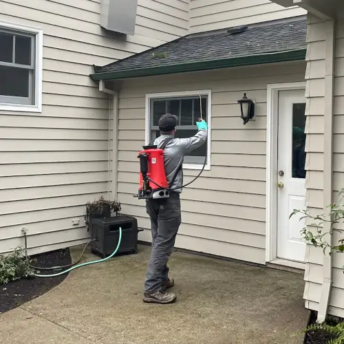 Pest Plus technician treating the exterior of a residential home in Multnomah County OR