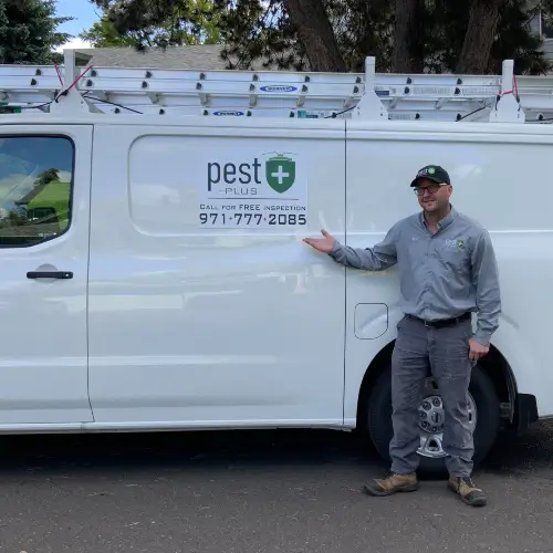 Pest Plus technician smiling and standing in front of their service vehicle in Gresham Butte OR